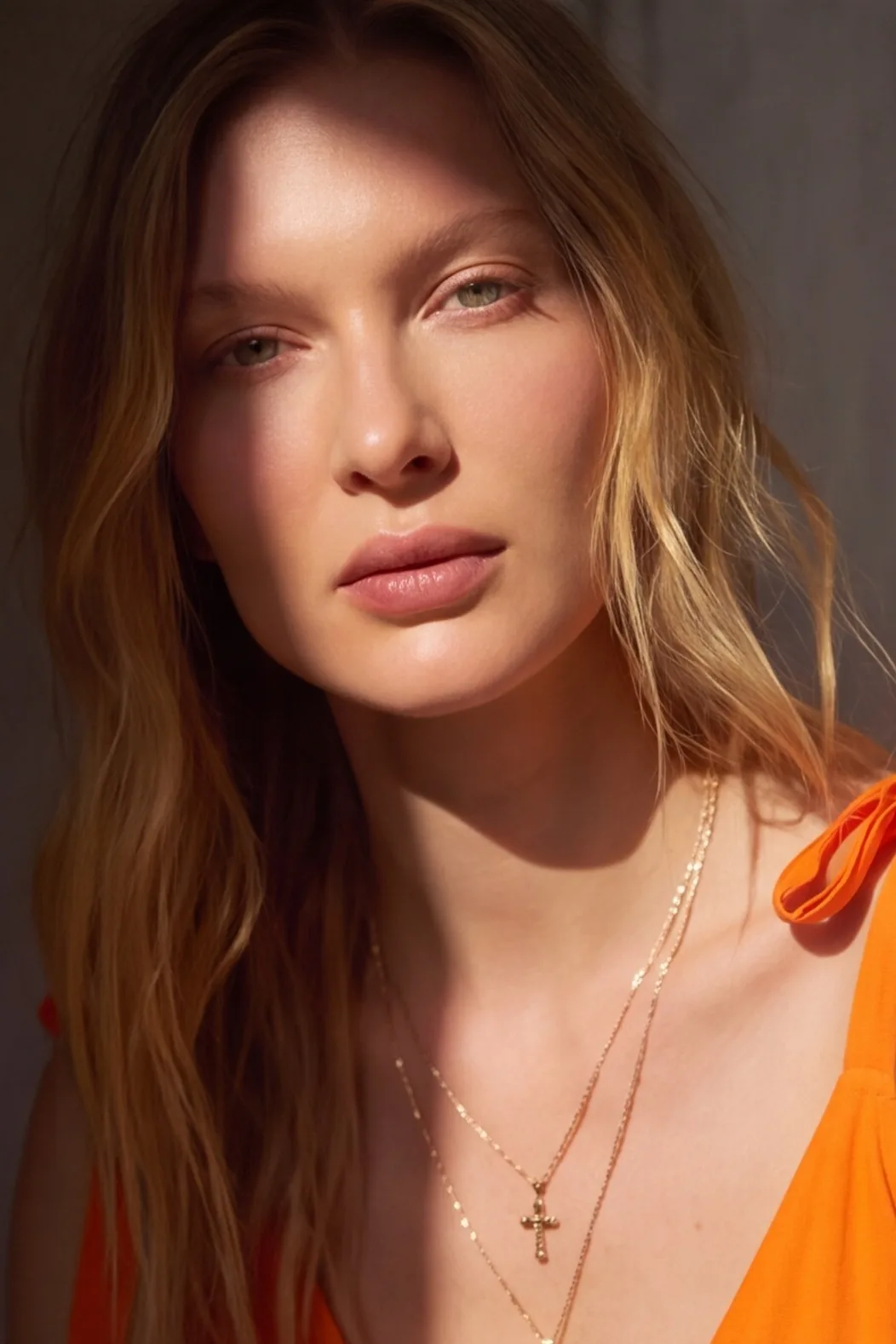 Modelo de vestido laranja com colar de crucifixo