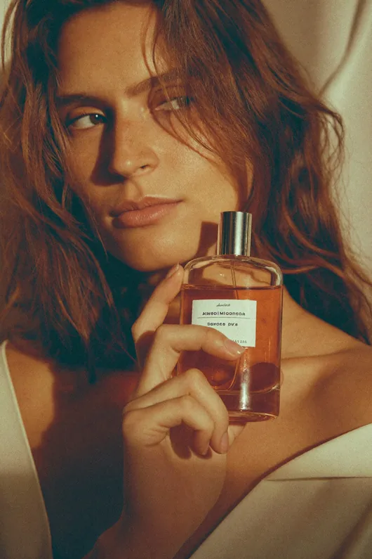 Modelo segurando um frasco de perfume